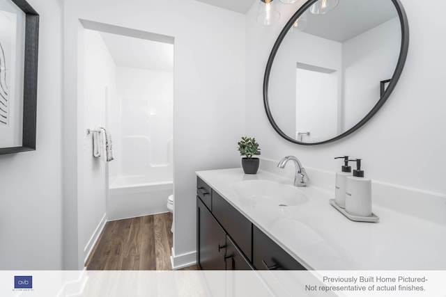 full bathroom with hardwood / wood-style flooring, shower / bathtub combination, vanity, and toilet