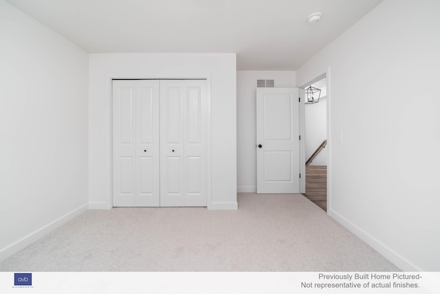 unfurnished bedroom with light colored carpet and a closet