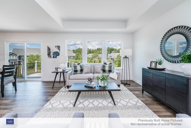 living room featuring dark wood-type flooring, plenty of natural light, and a tray ceiling