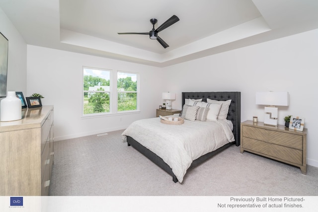 bedroom featuring ceiling fan, a tray ceiling, and light colored carpet