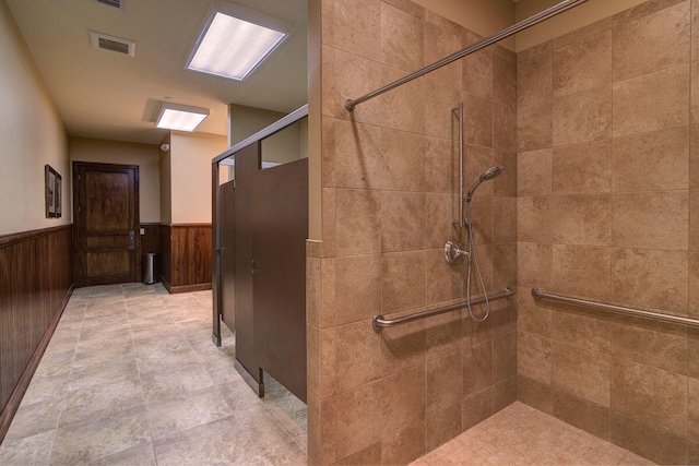 bathroom with a tile shower and wood walls