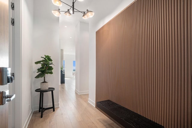 hall with a chandelier and light wood-type flooring