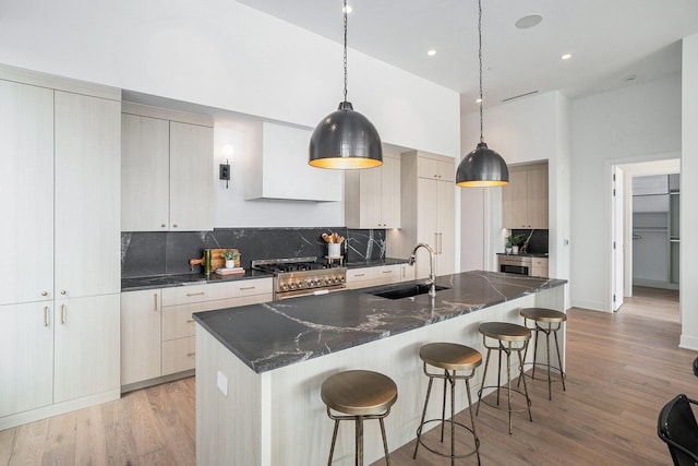 kitchen featuring a kitchen island with sink, hanging light fixtures, high end stove, and sink