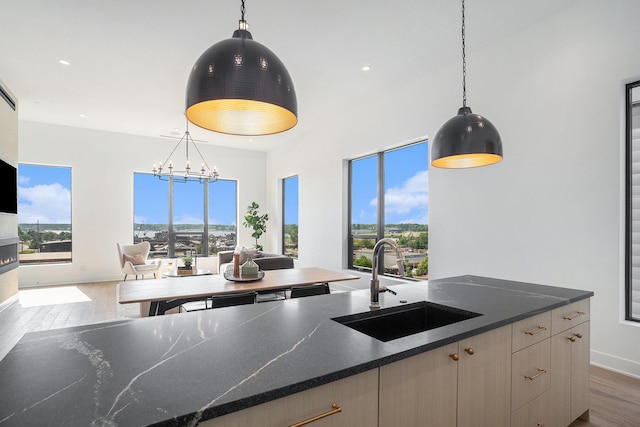 kitchen with pendant lighting, sink, dark hardwood / wood-style flooring, dark stone counters, and light brown cabinets