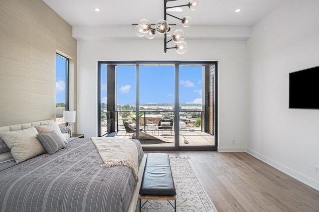 bedroom featuring access to exterior, hardwood / wood-style floors, and a notable chandelier