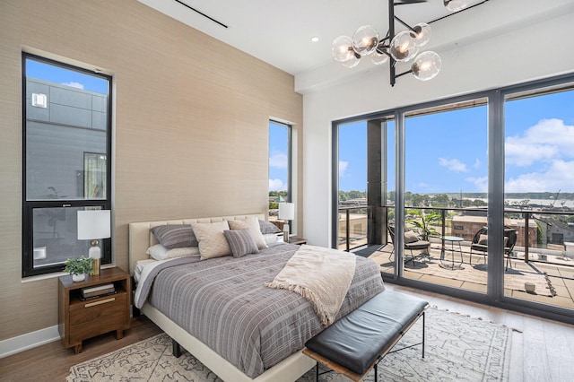 bedroom with hardwood / wood-style floors, access to outside, and an inviting chandelier