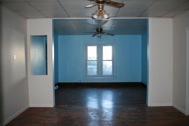 unfurnished room featuring ceiling fan, dark hardwood / wood-style floors, and a drop ceiling