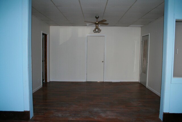 empty room featuring dark wood-type flooring, ceiling fan, and a paneled ceiling