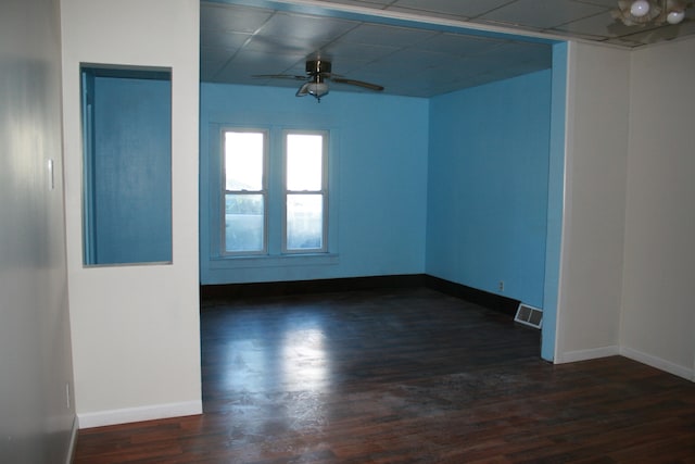 empty room with dark hardwood / wood-style floors, a paneled ceiling, and ceiling fan