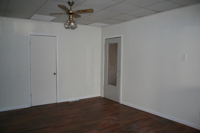 empty room with dark wood-type flooring, a paneled ceiling, and ceiling fan