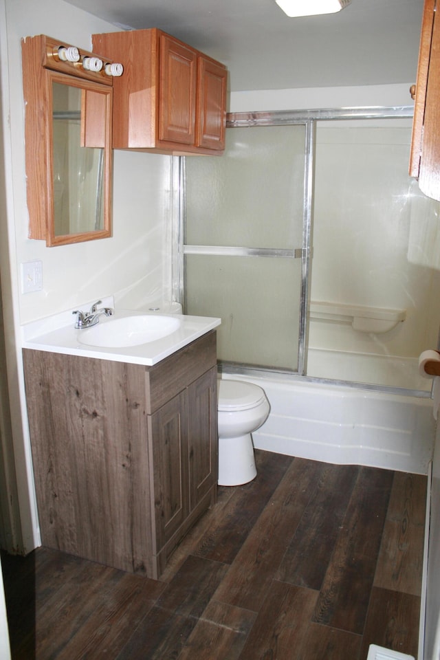 full bathroom featuring vanity, toilet, combined bath / shower with glass door, and hardwood / wood-style floors