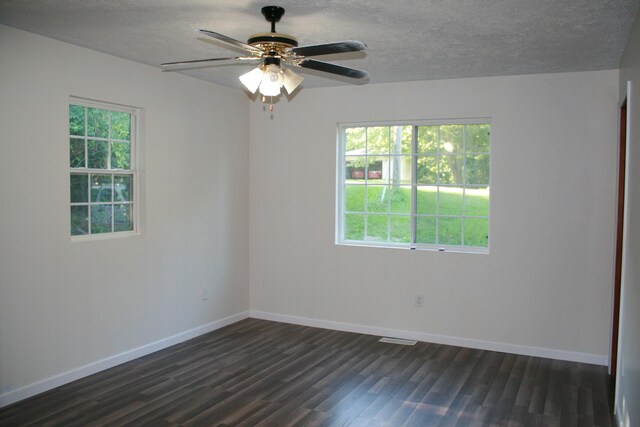 spare room featuring dark wood-type flooring, ceiling fan, plenty of natural light, and a textured ceiling