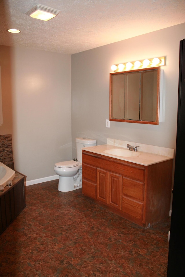 bathroom with vanity, toilet, and a textured ceiling