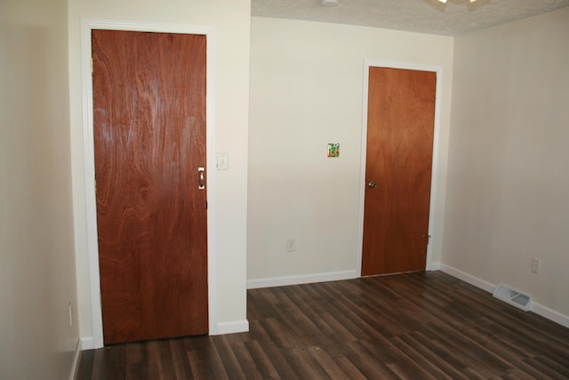 empty room with dark hardwood / wood-style flooring and a textured ceiling