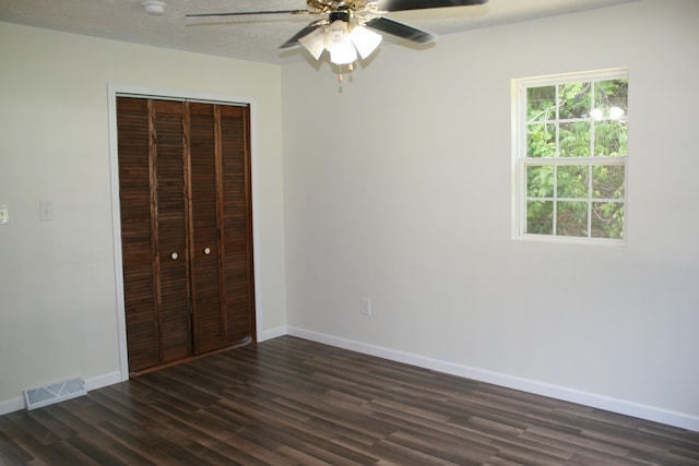 unfurnished bedroom with dark hardwood / wood-style flooring, ceiling fan, and a closet