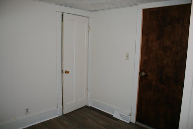 unfurnished room with dark hardwood / wood-style flooring and a textured ceiling