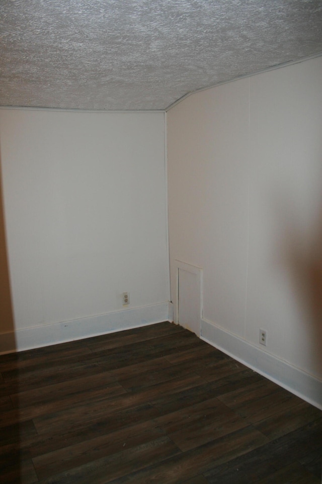 empty room with dark hardwood / wood-style flooring and a textured ceiling