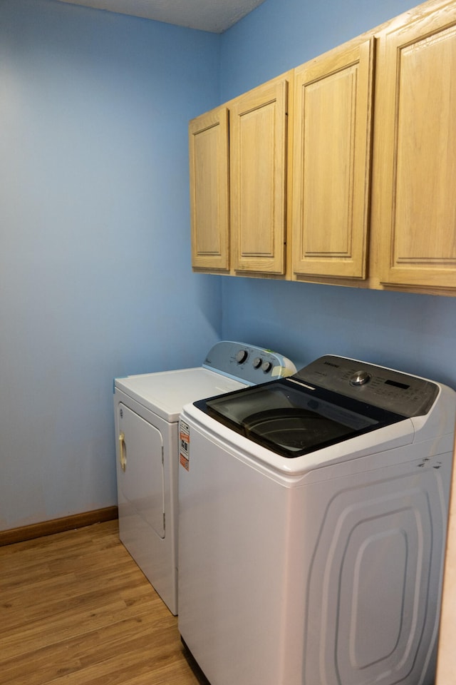 laundry room featuring cabinets, light wood-type flooring, and independent washer and dryer