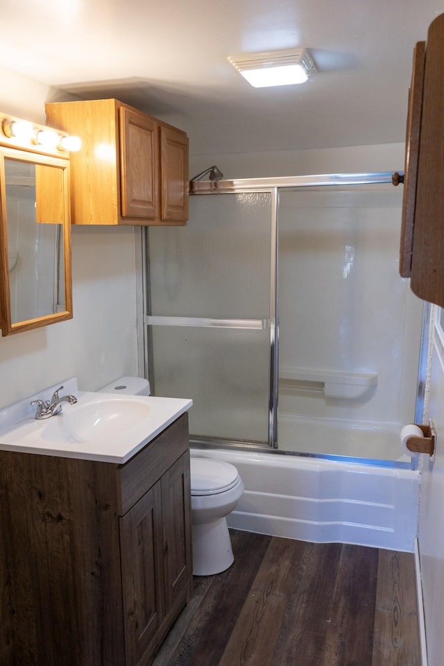 full bathroom featuring hardwood / wood-style flooring, vanity, bath / shower combo with glass door, and toilet