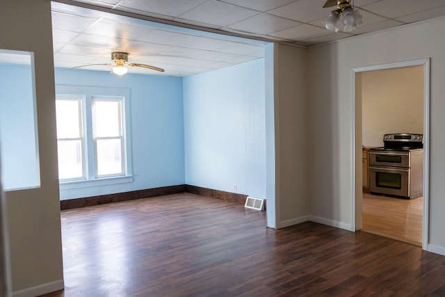 spare room featuring a drop ceiling, dark hardwood / wood-style floors, and ceiling fan