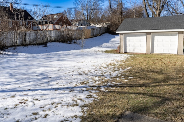 yard layered in snow featuring a garage and an outdoor structure