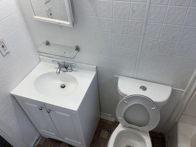 bathroom featuring vanity, tile walls, and toilet