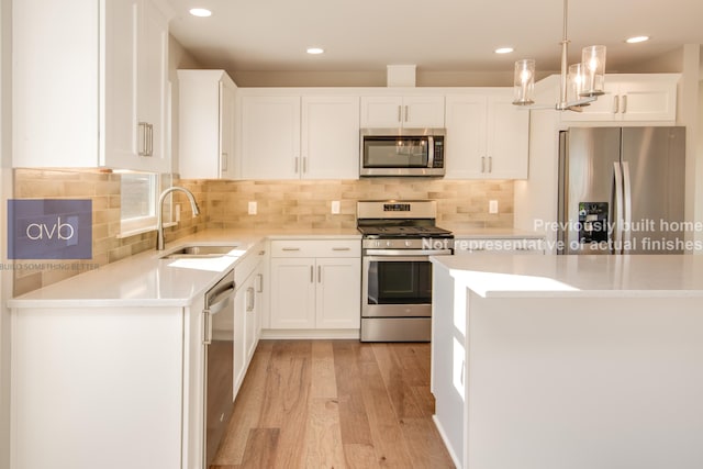 kitchen featuring hanging light fixtures, stainless steel appliances, sink, and white cabinets