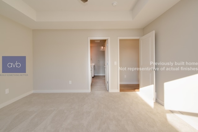 carpeted spare room with a raised ceiling