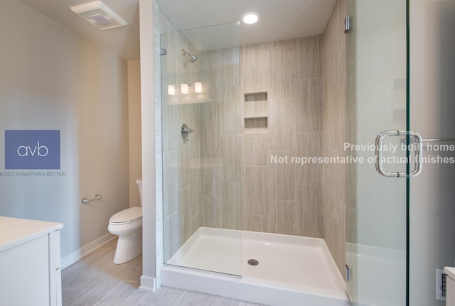 bathroom featuring vanity, a shower with shower door, and toilet