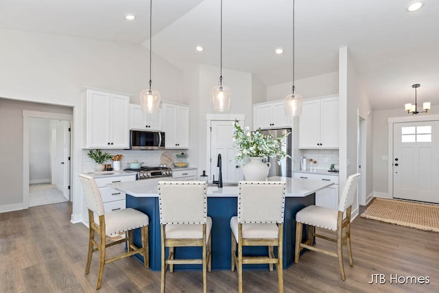 kitchen with an island with sink, stainless steel appliances, and white cabinetry