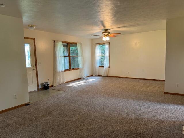 empty room with ceiling fan, a textured ceiling, and carpet flooring