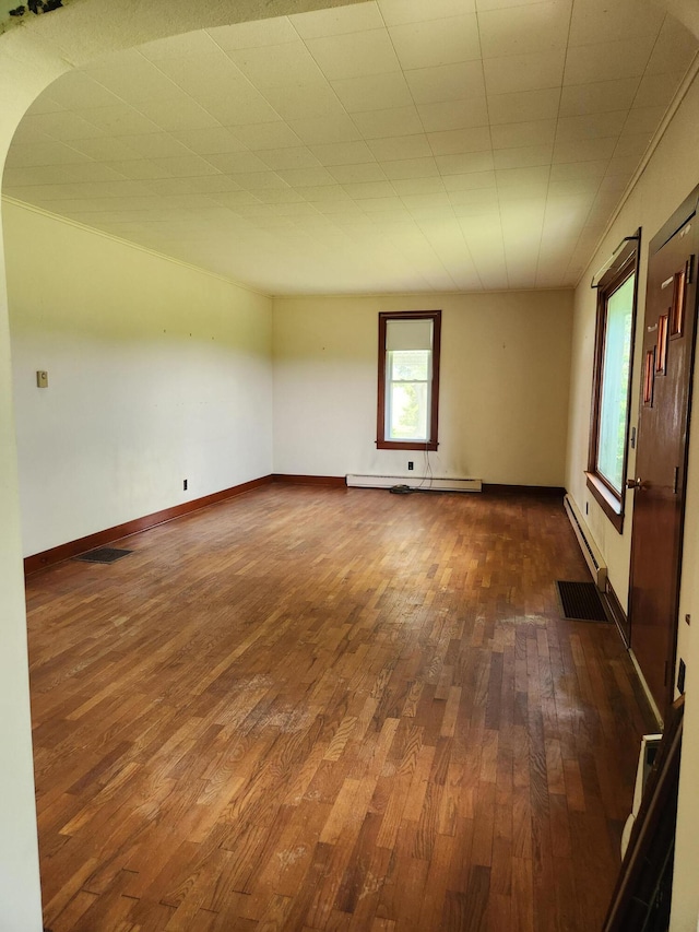 empty room with a baseboard heating unit and dark wood-type flooring