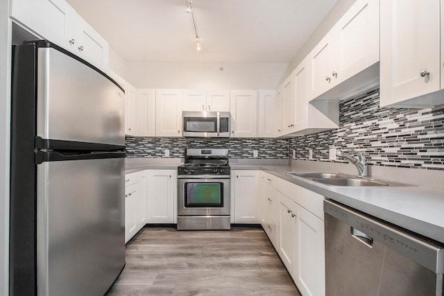 kitchen with tasteful backsplash, sink, light hardwood / wood-style floors, stainless steel appliances, and white cabinets