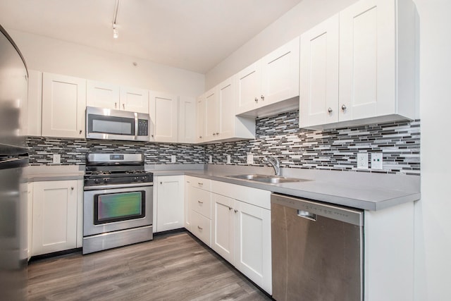 kitchen featuring appliances with stainless steel finishes, white cabinetry, sink, and hardwood / wood-style floors