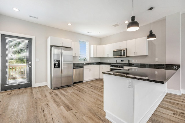 kitchen with light hardwood / wood-style flooring, white cabinetry, appliances with stainless steel finishes, and hanging light fixtures