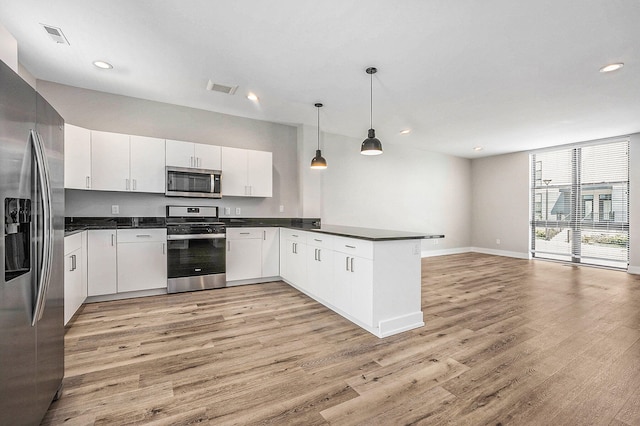 kitchen with appliances with stainless steel finishes, light wood-type flooring, kitchen peninsula, and white cabinetry