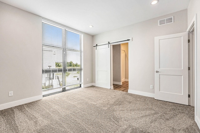 unfurnished bedroom with carpet and a barn door