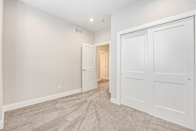 unfurnished bedroom with a closet and light colored carpet