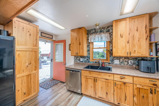 kitchen featuring dishwasher, black refrigerator, sink, and a wealth of natural light