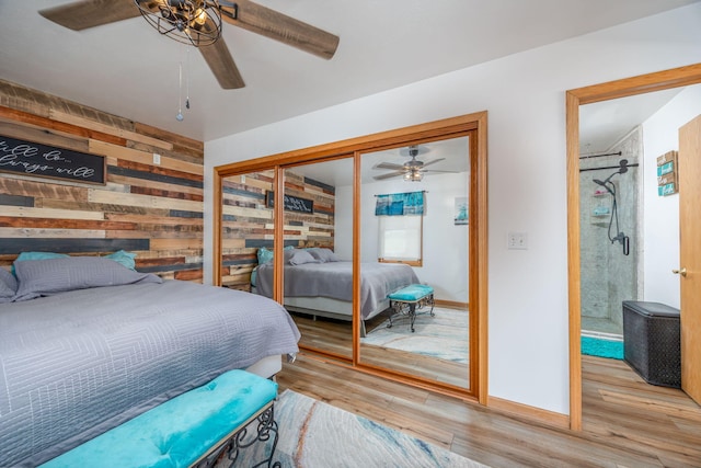 bedroom with light hardwood / wood-style flooring, wooden walls, a closet, and ceiling fan