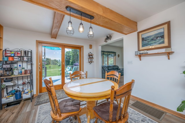 dining area featuring beamed ceiling and light hardwood / wood-style flooring