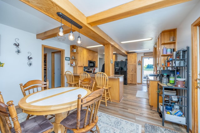 dining space featuring beamed ceiling, sink, and light hardwood / wood-style floors