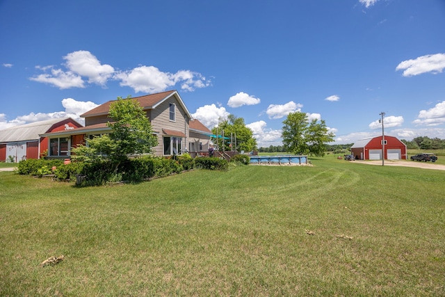 view of yard with a garage, a swimming pool, and an outbuilding