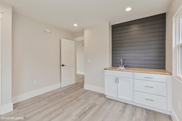 bar with sink, white cabinets, butcher block countertops, and light hardwood / wood-style floors