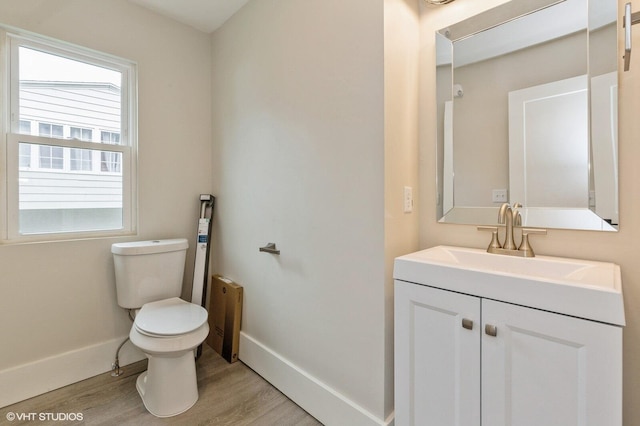 bathroom with wood-type flooring, vanity, and toilet