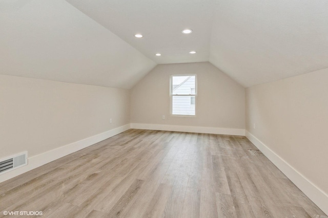 additional living space with vaulted ceiling and light hardwood / wood-style flooring