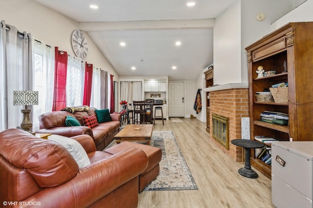 living room with a fireplace, lofted ceiling with beams, and light hardwood / wood-style flooring