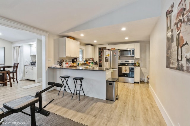 kitchen featuring vaulted ceiling, appliances with stainless steel finishes, white cabinets, and kitchen peninsula