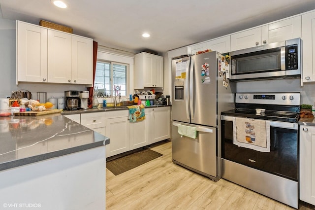 kitchen featuring sink, stainless steel appliances, light hardwood / wood-style floors, and white cabinets