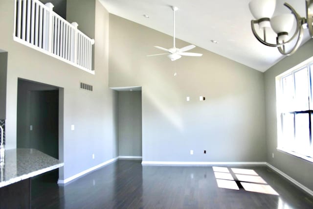 unfurnished living room with ceiling fan with notable chandelier, dark hardwood / wood-style floors, and high vaulted ceiling